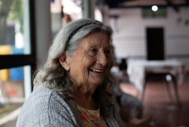 A woman with long gray hair smiling at the camera.