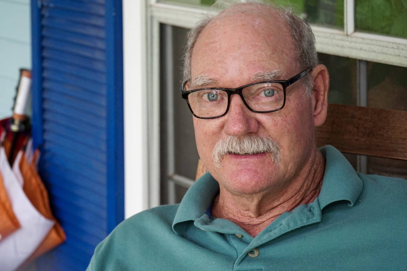 A man with glasses and a mustache wearing a blue shirt.